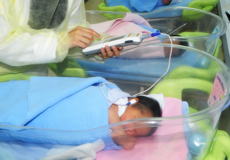 a nurse performing the Hearing Screening with an Echo-screen machine on a newborn